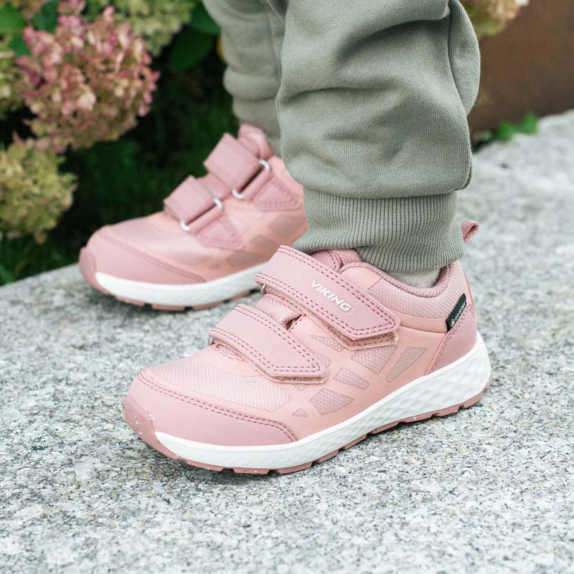 Nærbillede af pink børnesko med velcro, omgivet af grønt.