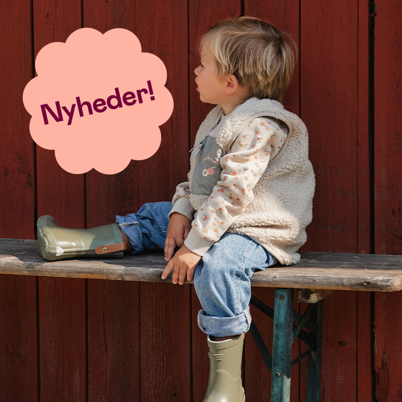 Barn i beige tøj ligger på gulvet med en sko op ad væggen.