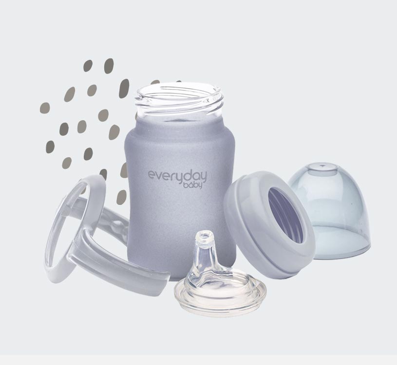 Grå sutteflaske med dele og mønstret baggrund.