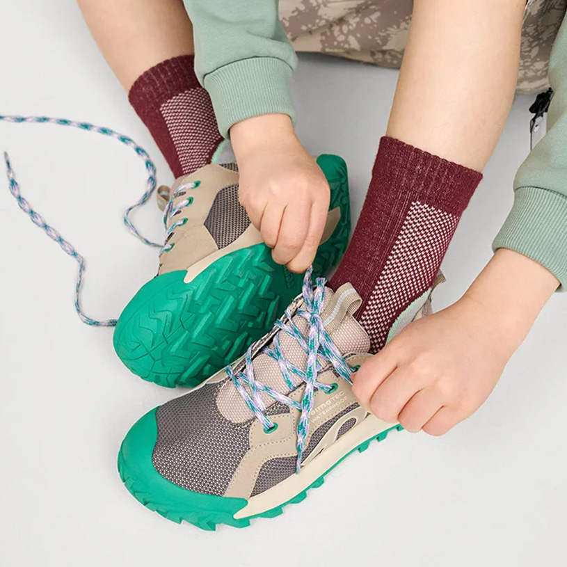 Børns brune sko med velcro og farverige bukser.