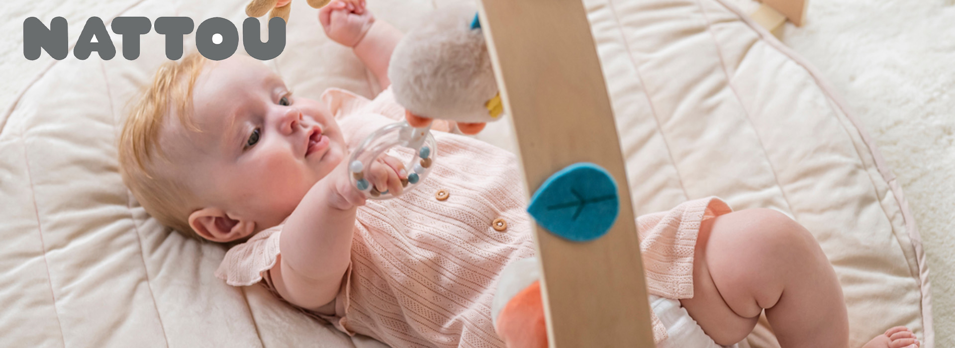 Baby leger med legetøj på blødt tæppe.