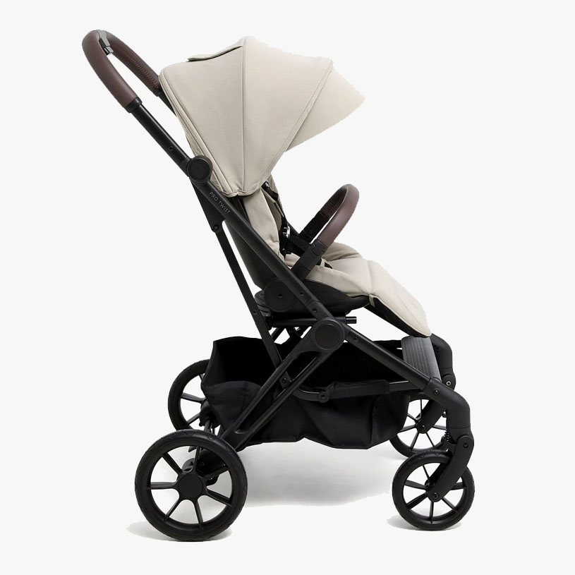 Sort klapvogn med gråt sæde og kaleche, står indendørs.