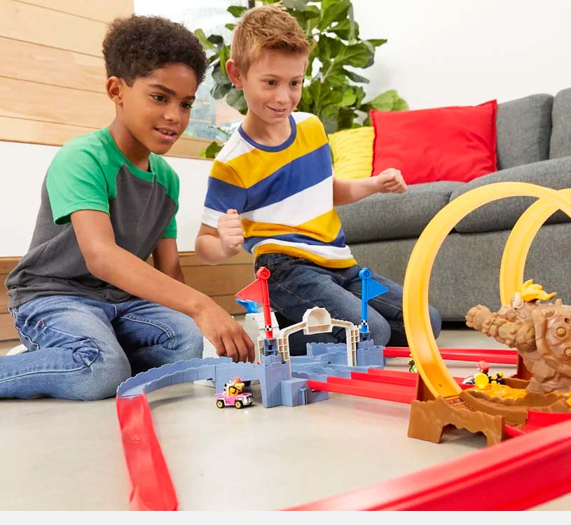 To drenge leger med en racerbane indendørs, med biler og loops.