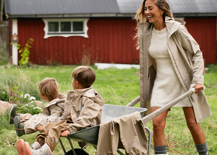 En kvinde trækker en skubbevogn med to børn, med teksten 'Kenza X Viking'.
