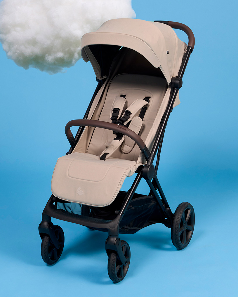 Barnevogn i beige farve med en sky i baggrunden.
