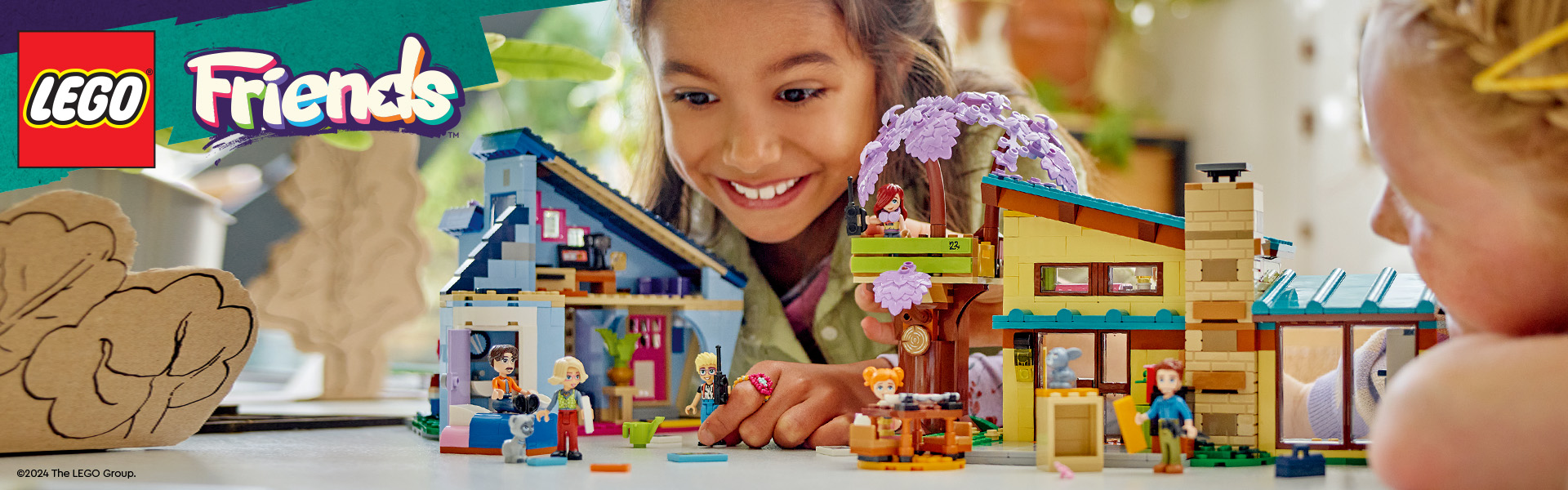 Børn leger med LEGO Friends dukkehus og figurer på et bord.