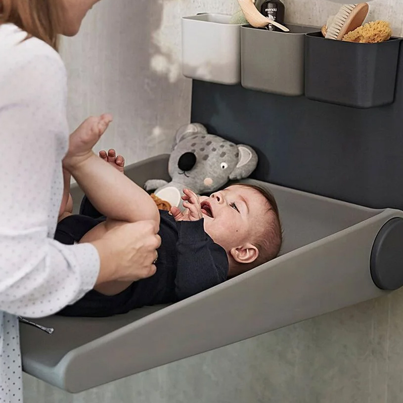 Hvidt vægmonteret skab med puslebord og hylder.