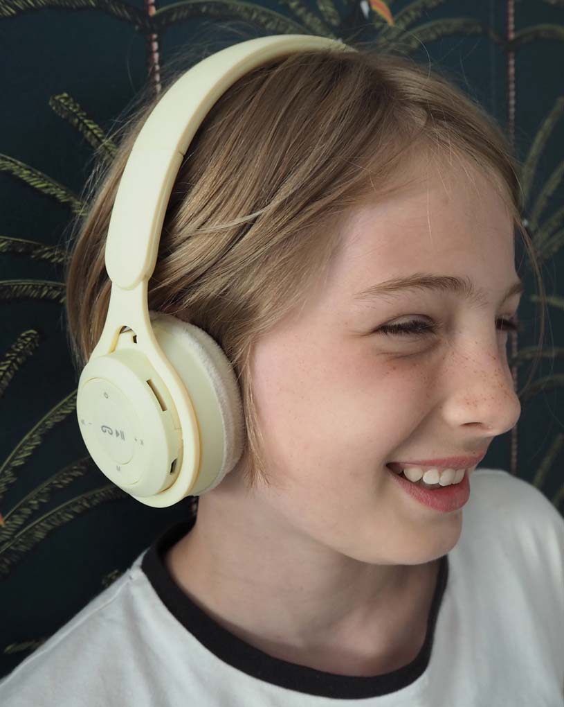 Barn med lyst hår bærer store høretelefoner og smiler.