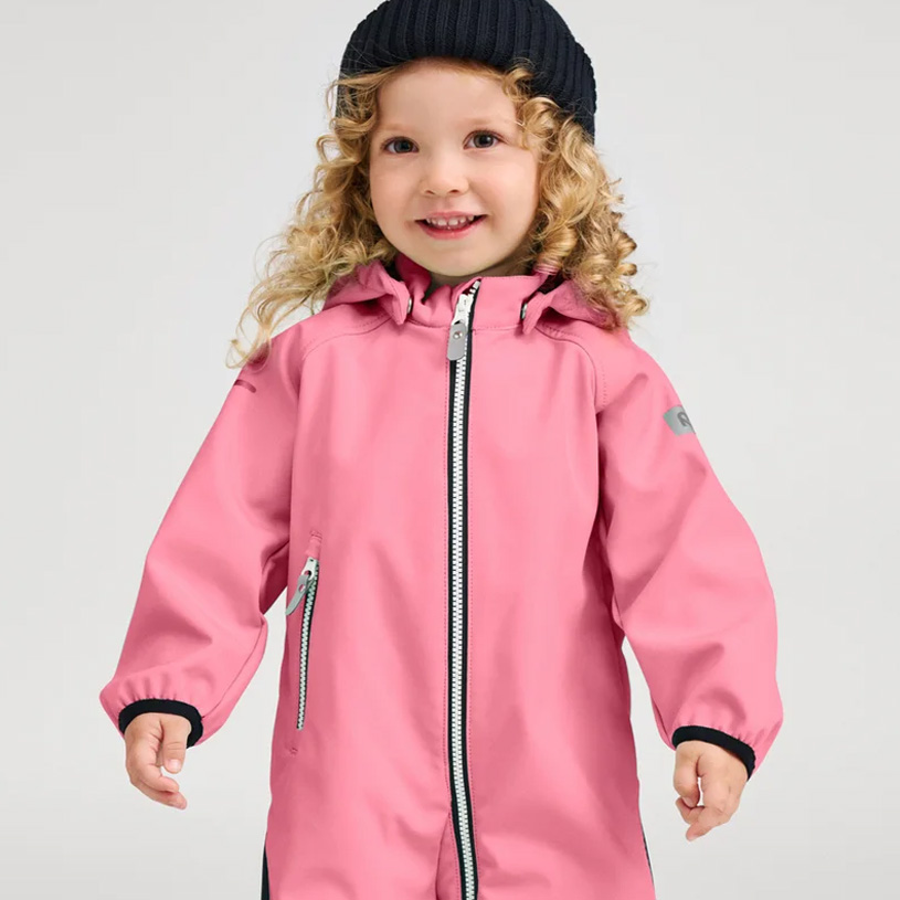 Smilende barn i orange jakke og lilla hue.