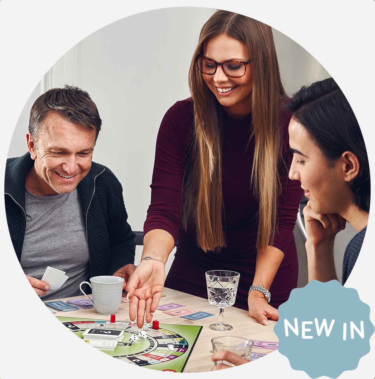 Tre personer spiller brætspil ved et bord.