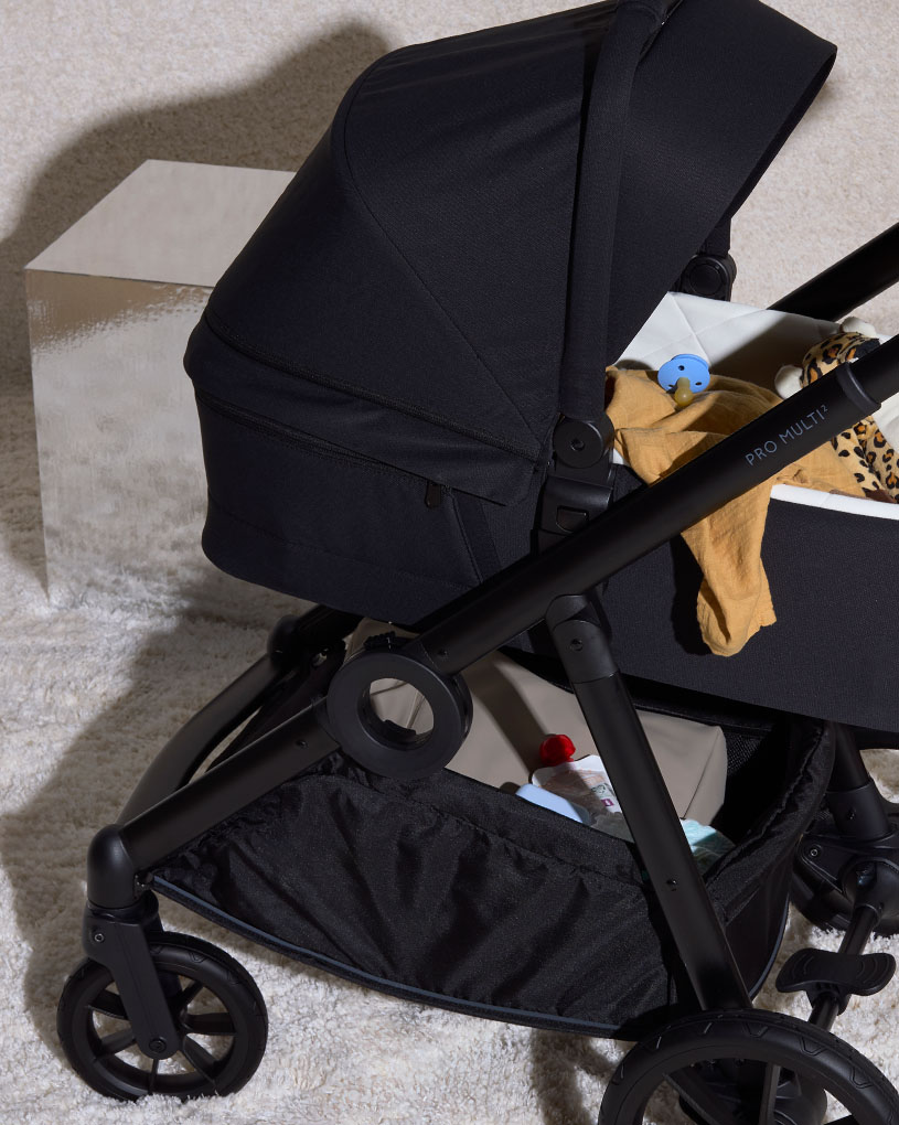 Sort klapvogn med en sutteflaske og en ble i opbevaringskurven.