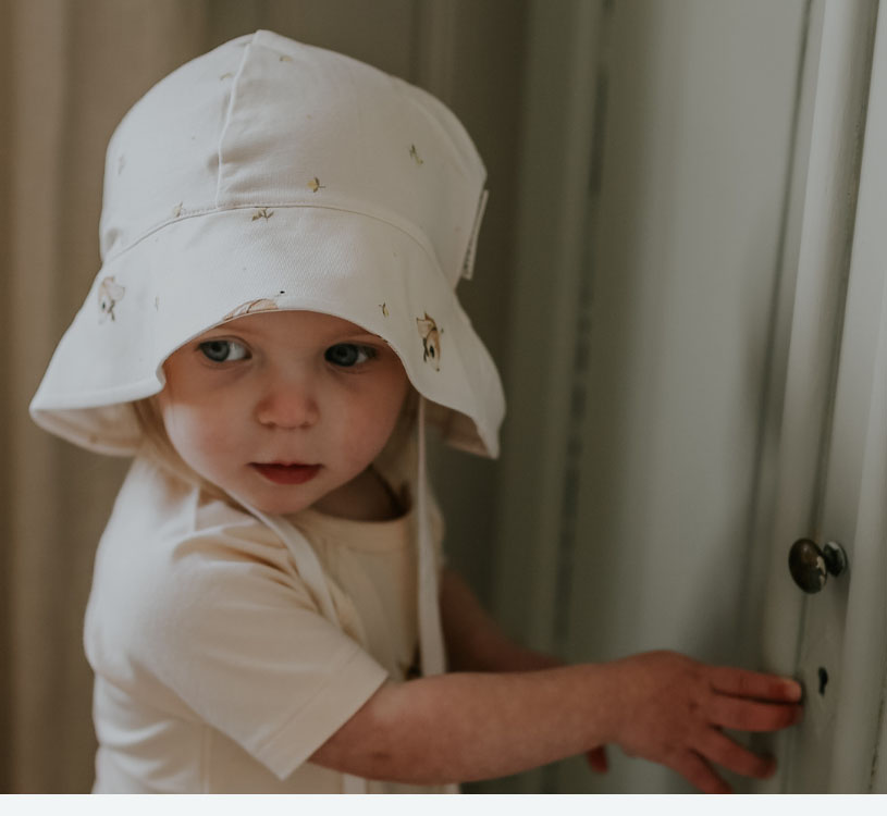 Lille barn i hvid hat kigger mod et håndtag.
