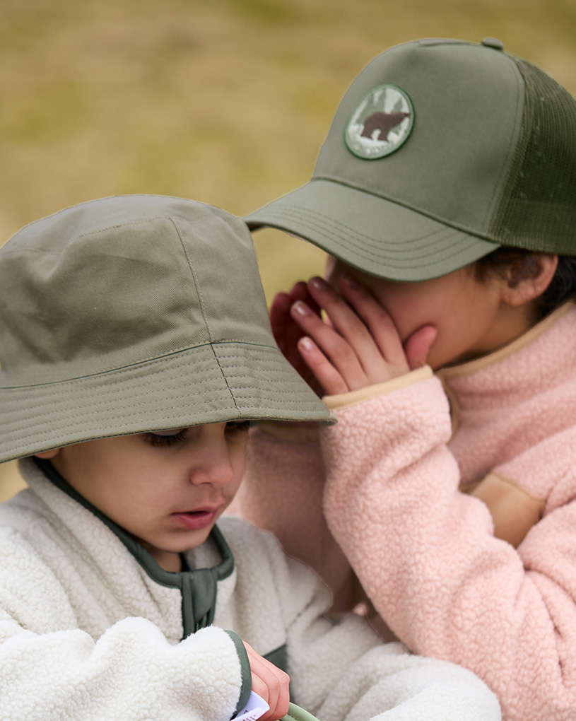 To børn i grønne hatte, en hvisker til den anden.