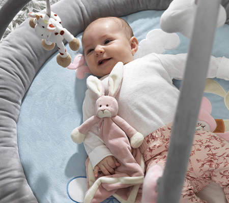 Leende bebis som ligger i ett baby-gym