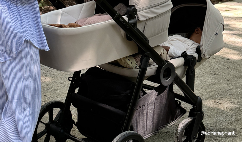 Detaljbild på en syskonvagn. Utomhus på promenad