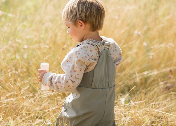 Barn i grå overalls holder en flaske, med teksten 'Kenza X Viking'.