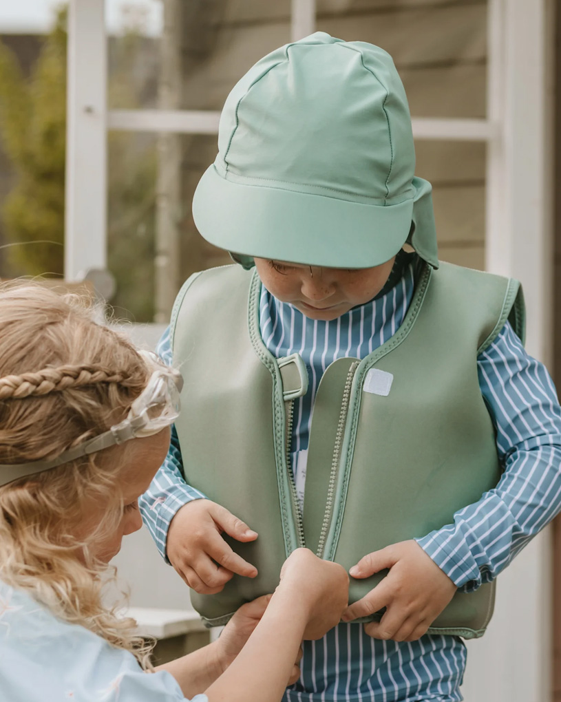 Børn i grønt tøj hjælper hinanden med en redningsvest.