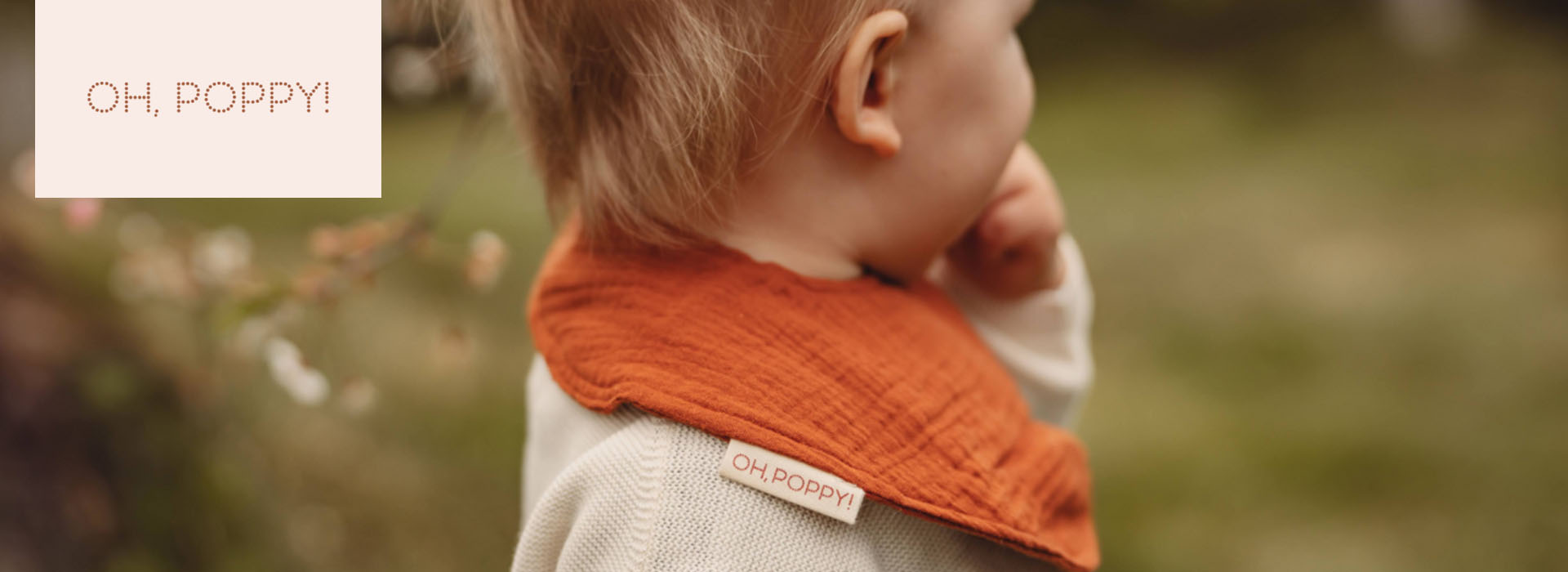 Barn med orange halsklæde, etiket "Oh, Poppy!"