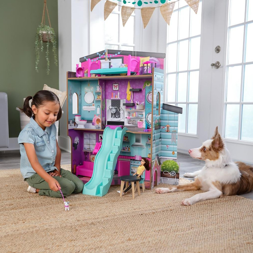 Pige og hund leger ved et dukkehus på gulvet.