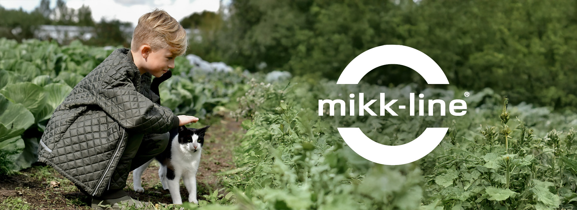 Dreng klapper kat i frodig have med mikk-line logo.