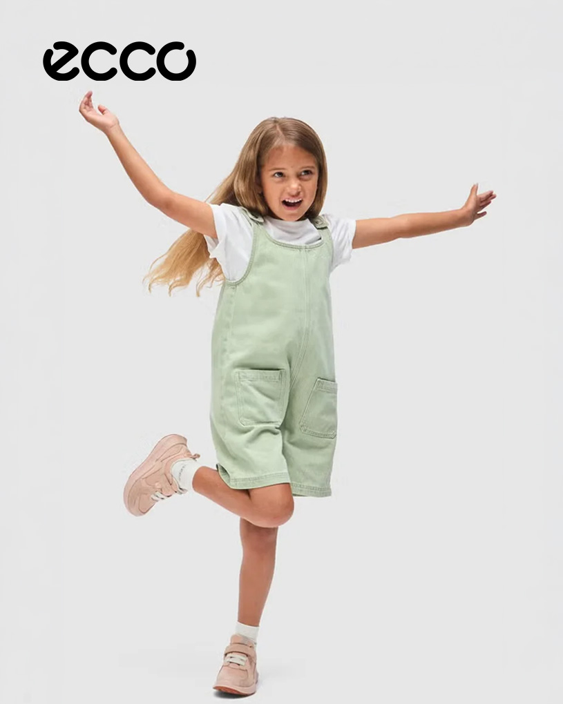 Glad pige i grønne seler hopper. "ECCO" ses øverst til venstre.