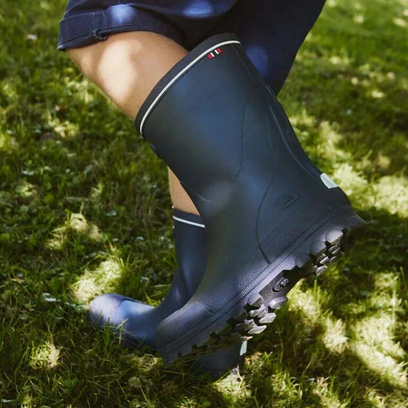 Grønne gummistøvler på våd overflade.