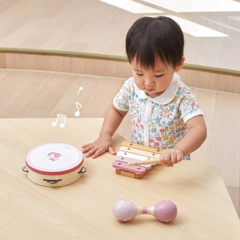Barn spiller på en xylofon ved et bord med tamburin og maracas.