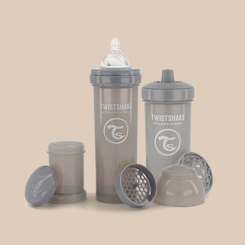 Grå Twistshake sutteflasker og tilbehør på beige baggrund.