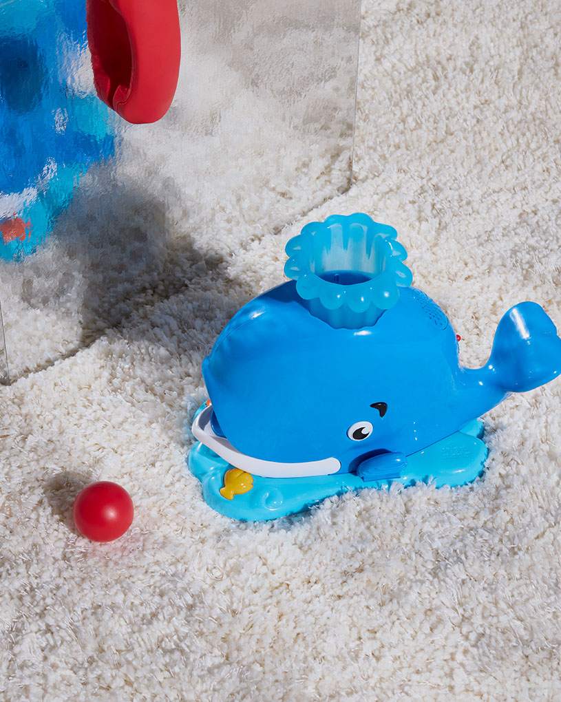 En blå hvallegetøj med en rød bold ved siden af, med teksten 'BabyWeeks'.