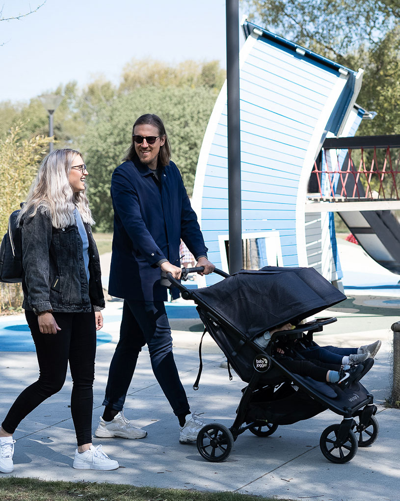 Mand og kvinde går med barnevogn udenfor.