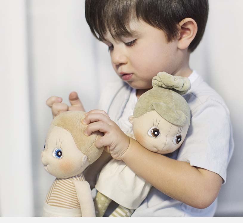 Barn, der holder to tøjdyr tæt ved sit ansigt.
