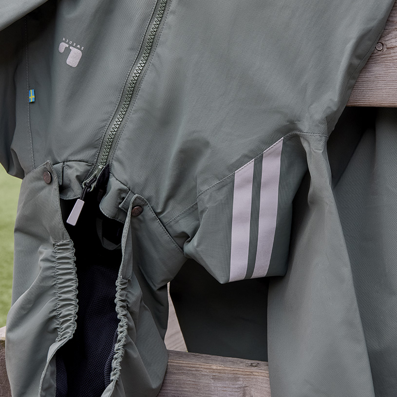 Barn i vintertøj og blå hue fokuserer på sine hænder.