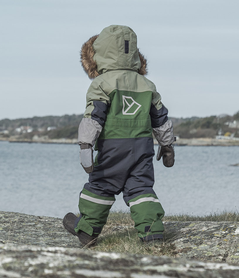 To børn i farverigt vintertøj står og smiler til kameraet.