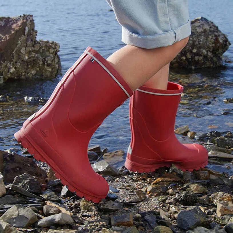 Person med røde gummistøvler på stenstrand.