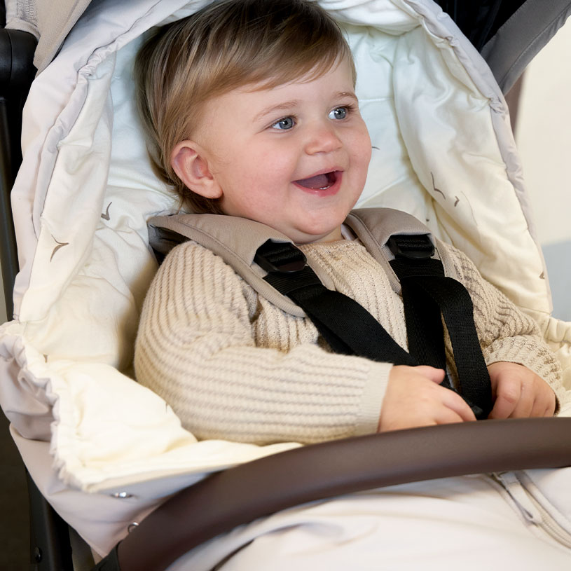 Barn i kørepose med blomstermønster og varm hue, splash med teksten "Nyheder!".