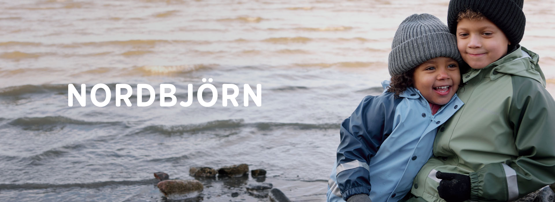 To børn i farverige tøj løber på en træsti gennem en græsmark.