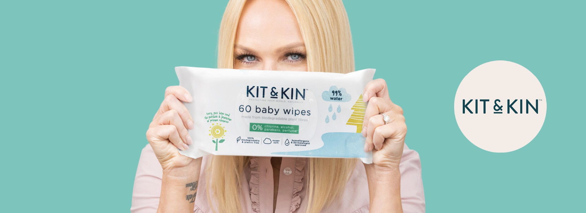 Person holder Kit & Kin babyservietter, turkis baggrund.