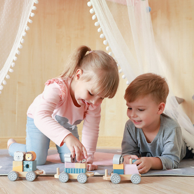 To børn leger med farverige trælegetøj under et telt.