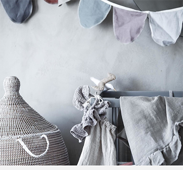 Neutral børneværelsesindretning med vævet kurv og flagguirlande.