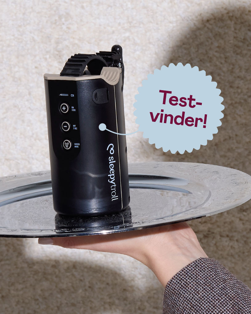 En hånd holder en sølvbakke med en sort enhed, med teksten 'Bedst i test'.