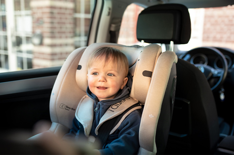 Smilende barn i autostol i bilen.