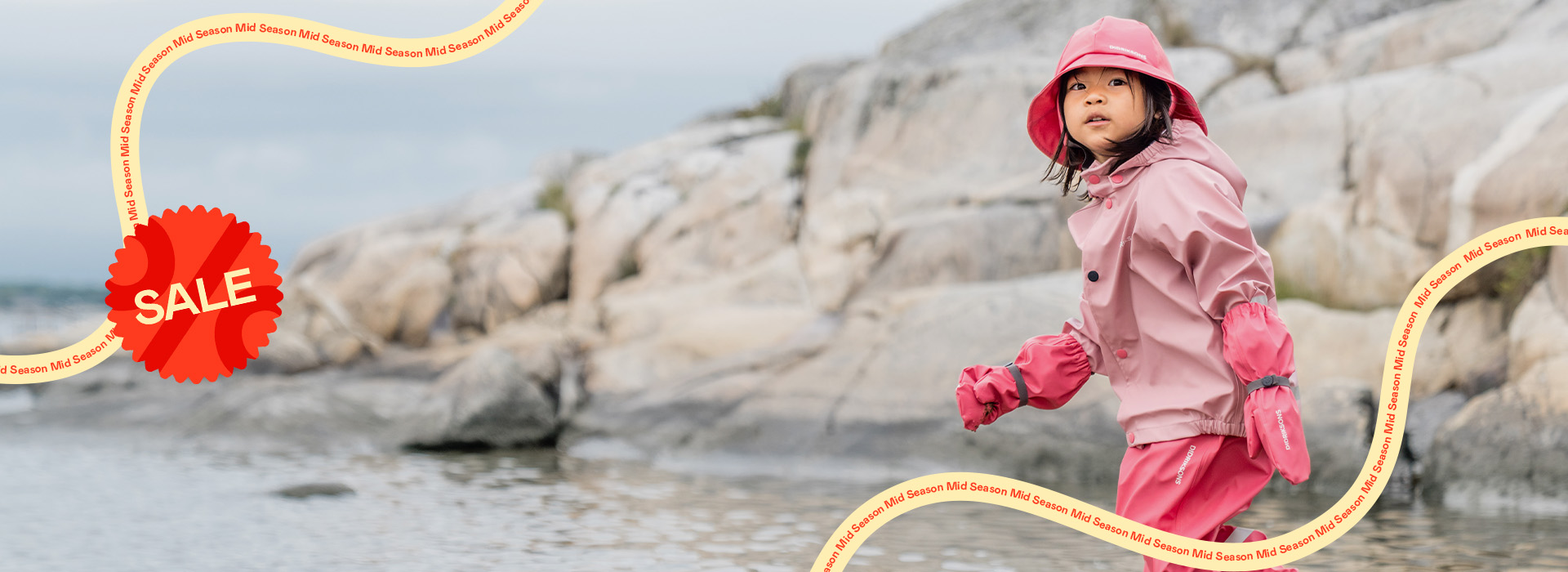 Barn i rosa regntøj går i vand, rød “SALE”-stempel nederst til højre