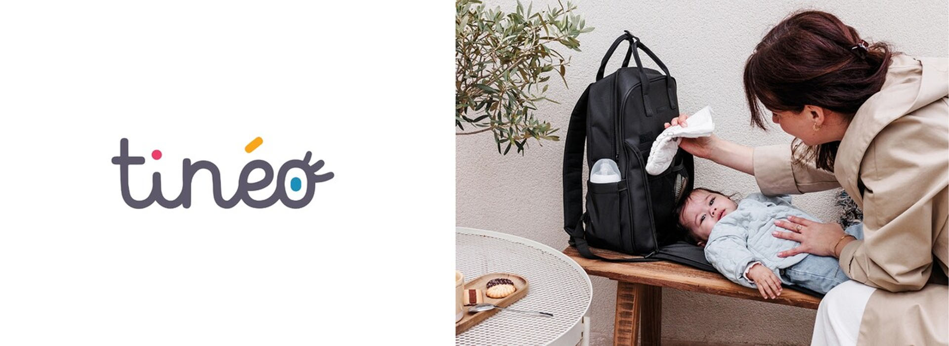 Mor tørrer en baby ved siden af en rygsæk og et bord.