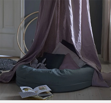 Hyggeligt hjørne med puder og kaniner under en lilla baldakin.