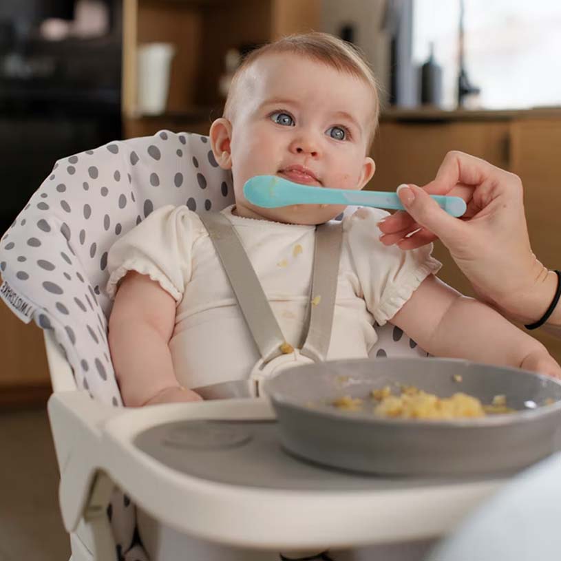 Baby sidder i højstol og bliver fodret med ske.