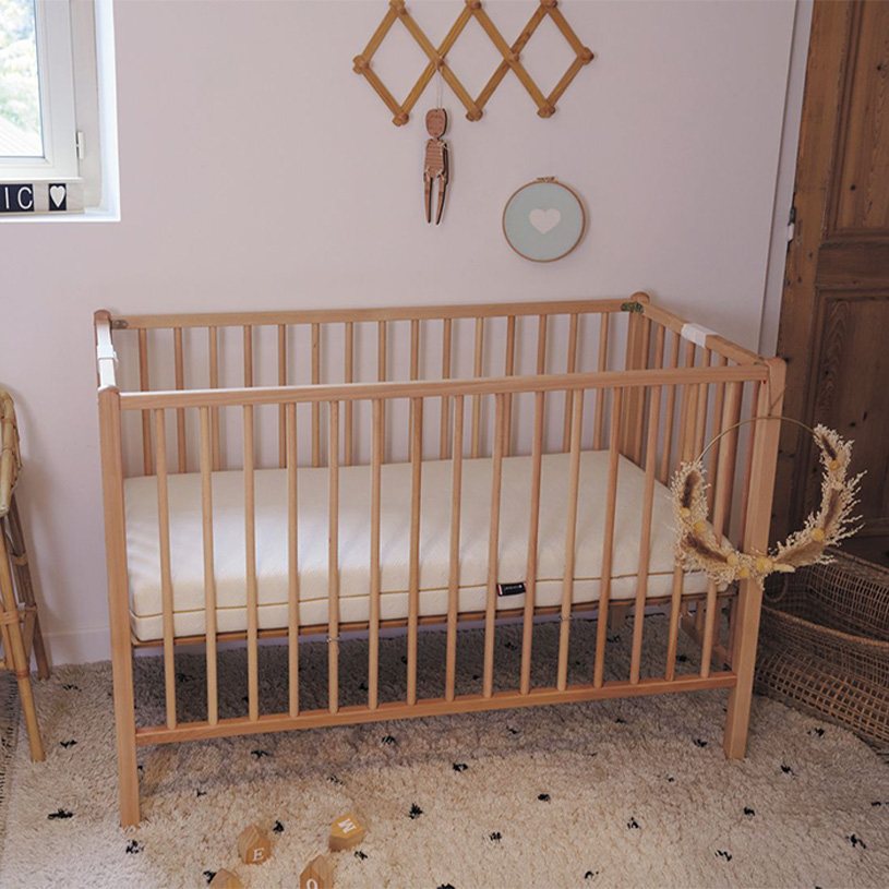 En træ tremmeseng med dekorationer på væggen ovenfor.