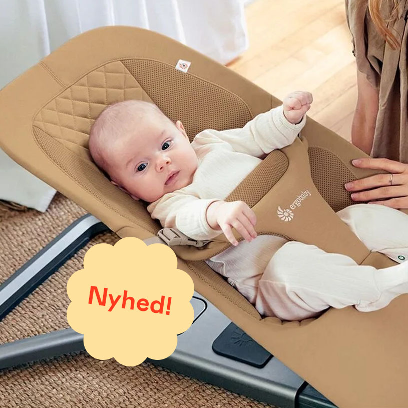 Baby i stribet pyjamas i skråstol med teksten 'Nyhed!' på lilla mærkat.