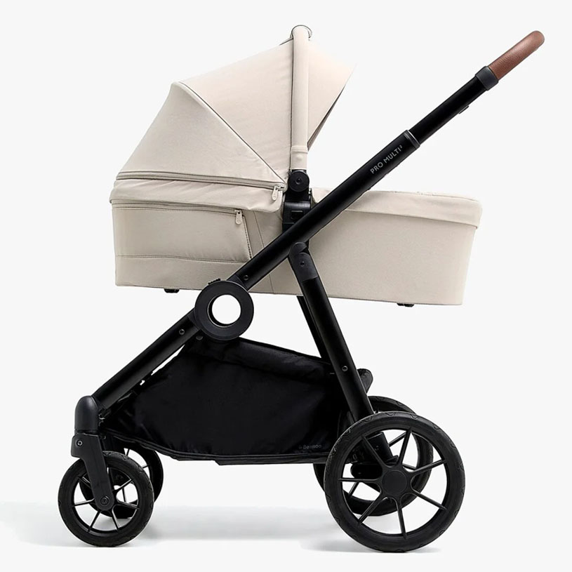 Grå barnevogn med to dele: liggedel og sittedel ved siden af et bord.