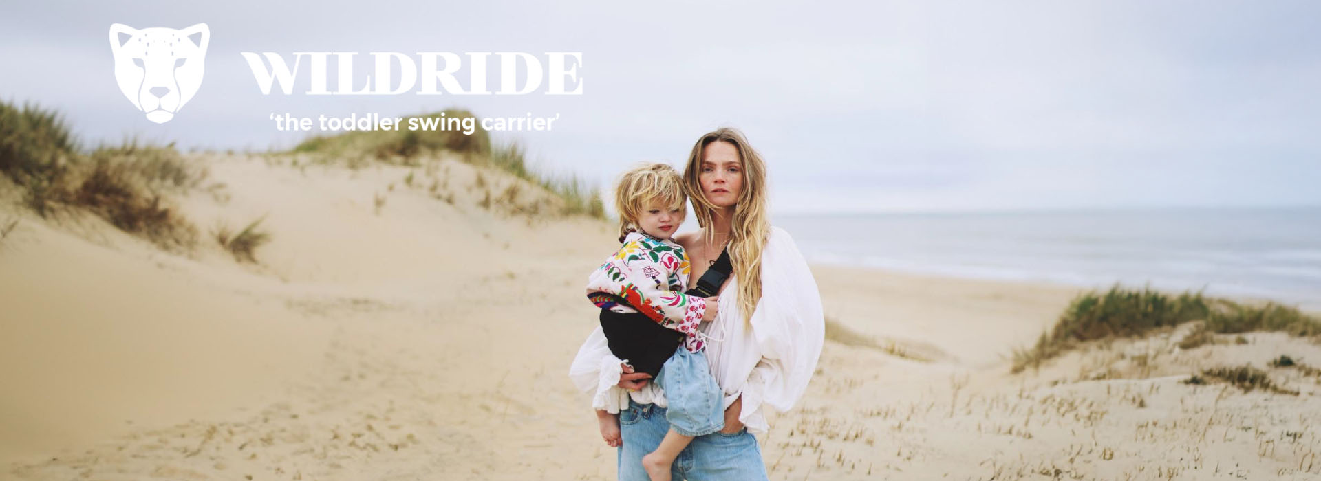 Mor og barn på strand, Wildride bæresele reklame.