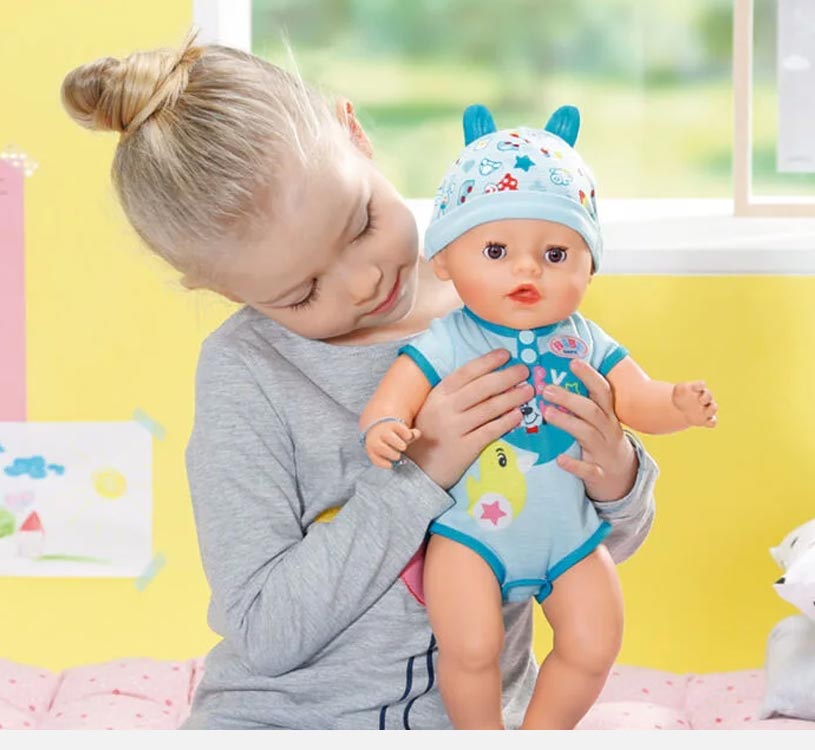 Pige holder en dukke i blåt tøj med hue med ører.